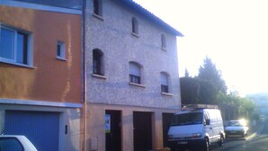 A two-story building with a garage on the ground floor and a white van parked in front. - 1 Bedroom Apartment in Le Bouscat (Le Bouscat)