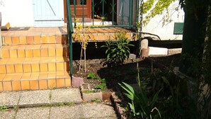 A paved pathway leading to a house entrance with a brick wall and a green metal gate. - 1 Bedroom Apartment in Le Bouscat (Le Bouscat)