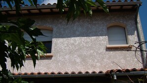 A two-story building with a textured facade, a tiled roof, and a small arched entrance. - 1 Bedroom Apartment in Le Bouscat (Le Bouscat)