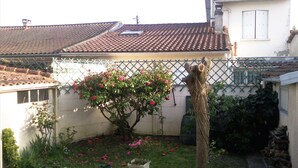 A residential garden with a potted plant, a tree, and a fence. - 1 Bedroom Apartment in Le Bouscat (Le Bouscat)