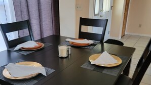 Ein Esstisch mit vier Stühlen, einer Kerze, Salz- und Pfefferstreuern sowie einer Tischmatte.