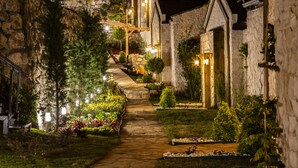 A stone pathway leading to a row of stone buildings with wooden accents and outdoor lighting. - Vista Del Amor Faralya (Fethiye)