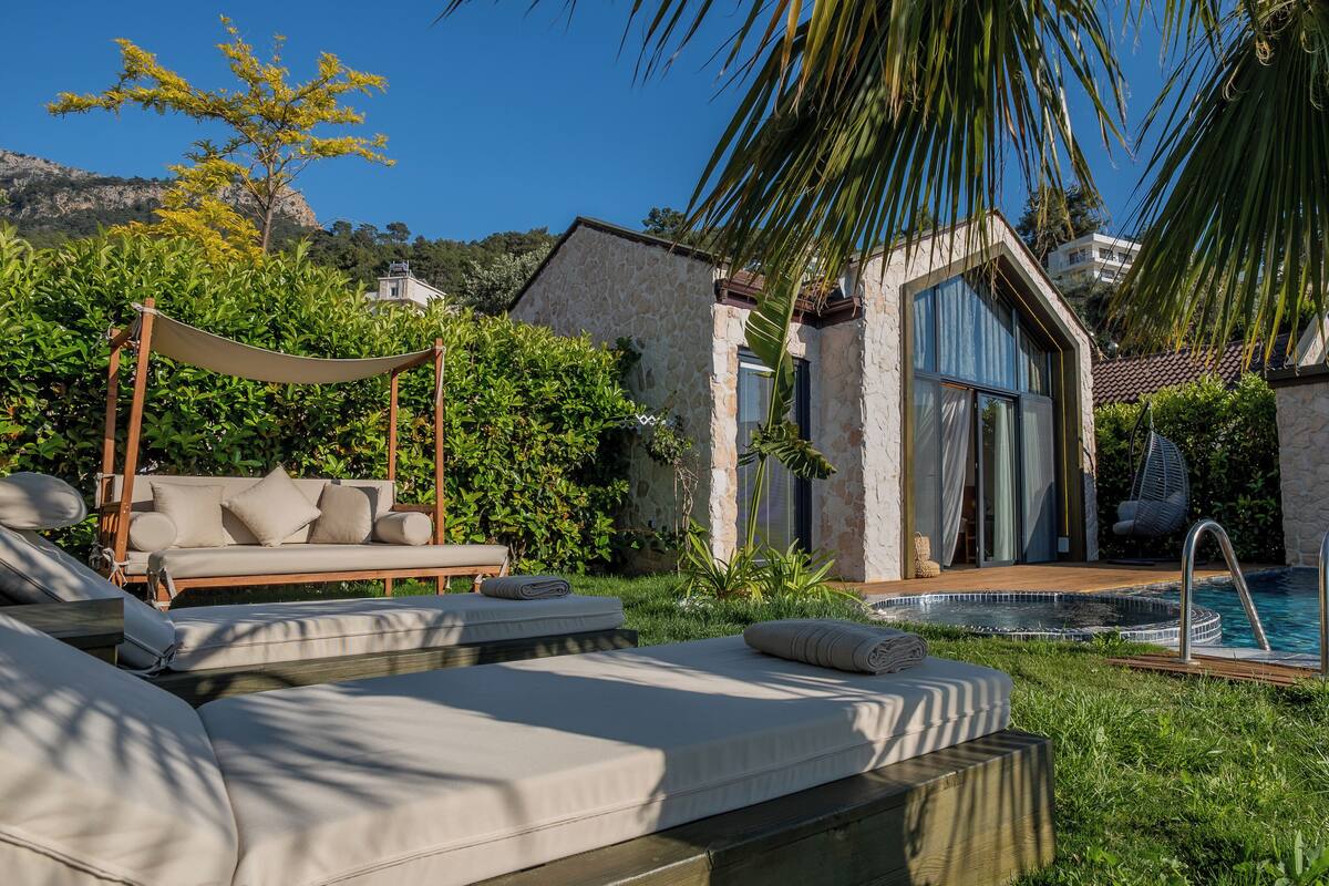 A poolside area with a sofa, a hanging chair, and a stone wall.