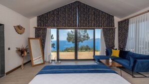 A modern bedroom with a large bed, a blue sofa, and a view of the sea. - Vista Del Amor Faralya (Fethiye)