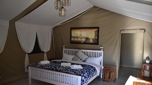 A bedroom with a white bed, a painting of a bridge, and a tent-like structure. - Camp Cedar (Baijnath)