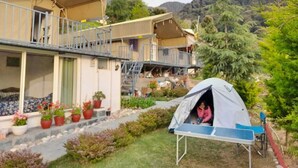 A house with a balcony, a tent, and potted plants in the yard. - Camp Cedar (Baijnath)