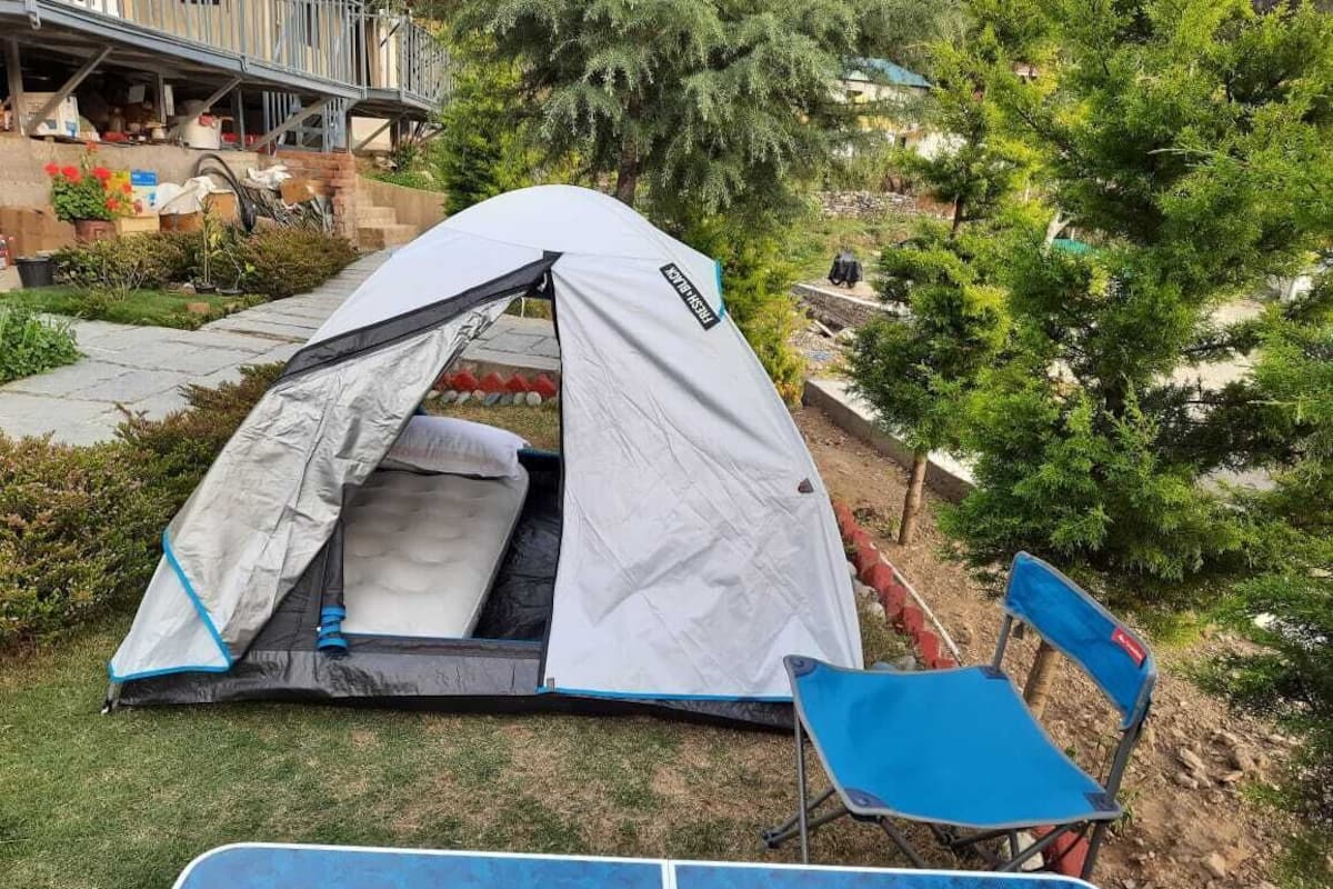 A tent set up in a grassy area with a blue chair nearby.