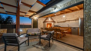An outdoor patio with seating, a stone fireplace, and a kitchen area. - Villa Petar ZadarVillas (Donji Kašić)