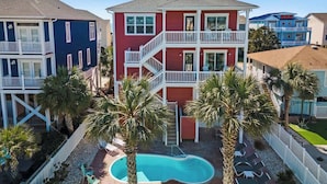 A multi-story residential building with a swimming pool, balconies, and palm trees.