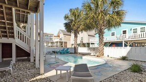 A pool area with a lounge chair, a small table, and a palm tree.