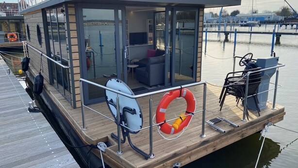 Un barco moderno con cabina de cristal, zona de estar y un flotador.