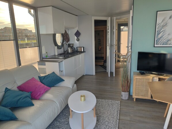 A modern living room with a sofa, a small round table, and a television.