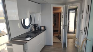 Una cocina moderna con horno empotrado, cafetera y tostadora. Hay una ventana que proporciona luz natural, y una puerta que da a un interior de madera.