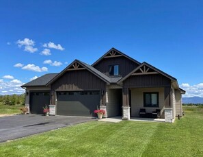 A two-story house with a garage, a covered porch, and a well-maintained lawn.