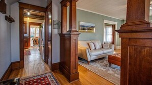 Uma sala de estar espaçosa com um sofá bege, um pilar de madeira e um quadro grande na parede.