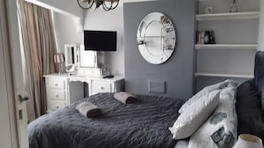 Un dormitorio con cama, escritorio, televisor y espejo.