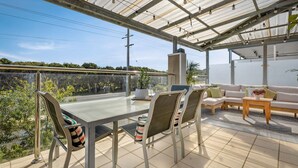 A conservatory with a glass ceiling, a dining table with chairs, a sofa, and a small table with a vase. - Back Beach Beauty in Smiths Beach (Smiths Beach)