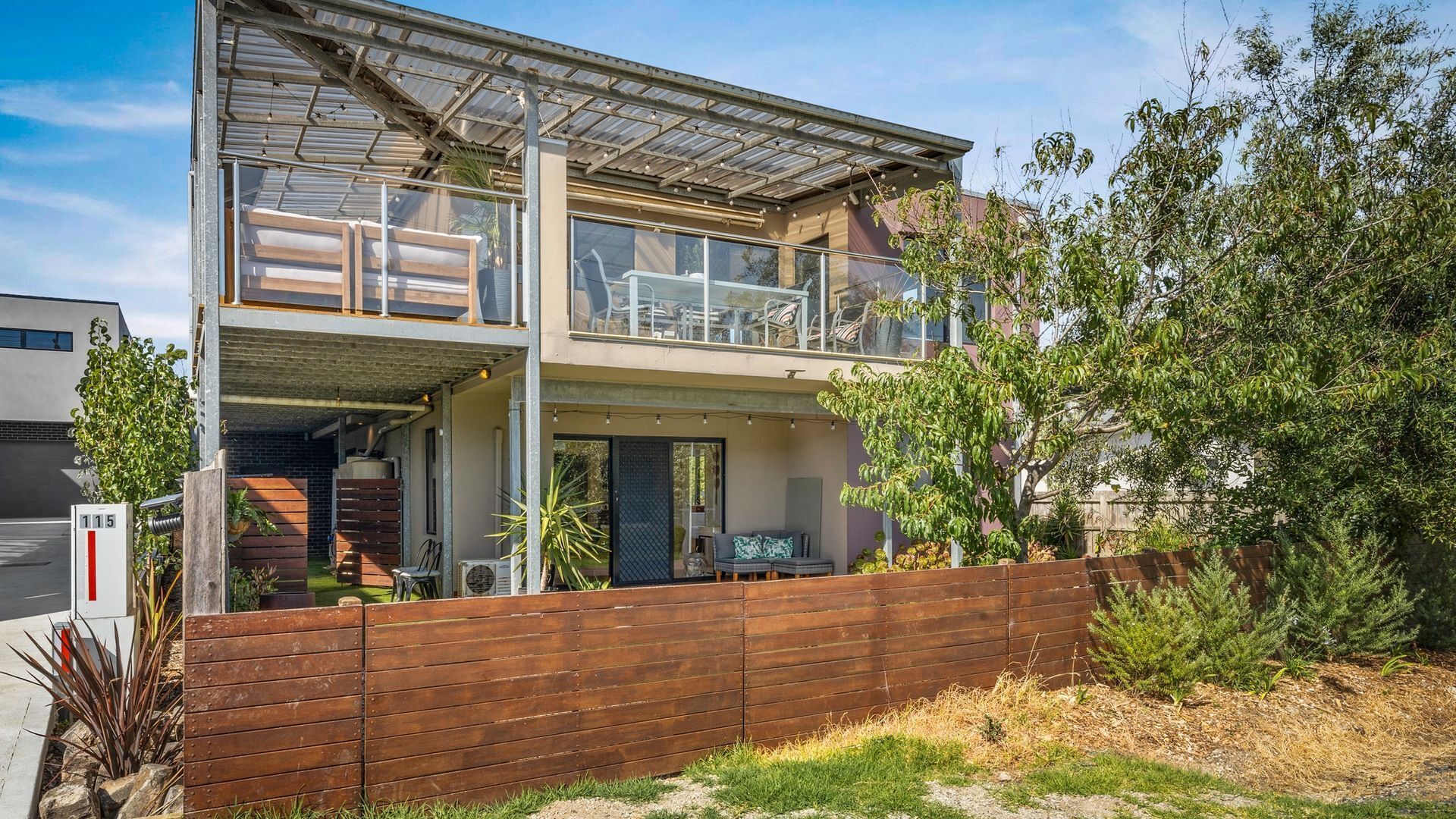 Een tweelaags huis met een balkon, een garage en een houten omheining.