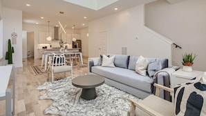 Uma sala de estar moderna com sofá, mesa de centro e área de jantar com cadeiras e mesa.