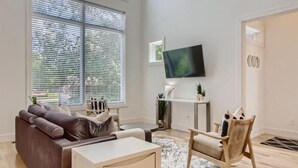 Uma sala de estar moderna com um sofá, mesa de centro e televisão sobre um móvel.