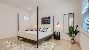 A modern bedroom with a four-poster bed, a large mirror, a 'LOVE LOVE' artwork, and a potted plant. - 17- Home w/ Rooftop - The Music City Collection (Nashville)