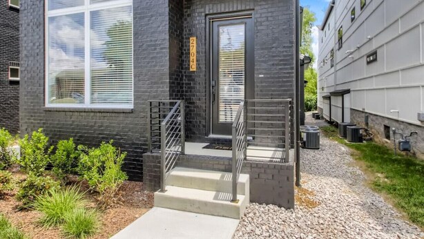 A modern building with a black brick exterior, a large window, and a door with a sign above it. - 17- Home w/ Rooftop - The Music City Collection (Nashville)