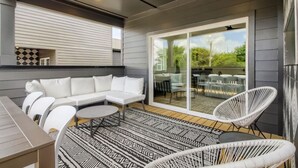 A modern outdoor patio with a white sofa, white chairs, a round table, and a patterned rug. - 17- Home w/ Rooftop - The Music City Collection (Nashville)