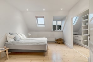 Une chambre à coucher comprenant un lit, une table de chevet, une fenêtre et des rangements intégrés.