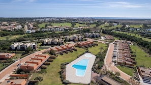 A residential area with modern apartment buildings, a swimming pool, and a view of the sea. - Apart L'Orange - A Luxurious Vacation Retreat (Quarteira)