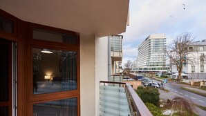 Un balcón con vistas a un edificio moderno y un estacionamiento.