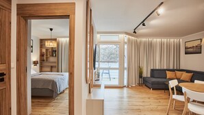 Una sala de estar moderna con una cama, un sofá, una mesa de comedor y un ventanal grande.