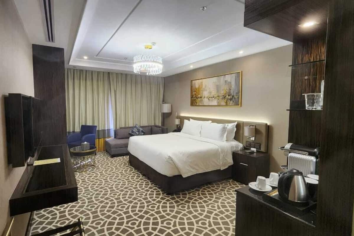 Ein Hotelzimmer mit einem großen Bett, einem Schreibtisch mit Stuhl, einem Fernseher und einer Kandelaber.
