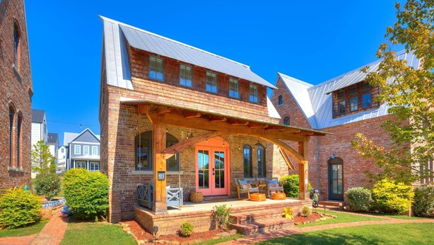 A brick house with a porch, a red door, and a small garden. - Carlton Landing-The Coral Cottage (Carlton Landing)