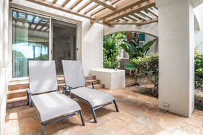 A patio area with two grey cushioned chairs, a small table, and a pergola structure. - Palms at Wailea #1605 Tropical Garden View Ground Floor, Wifi, Shared Hot Tub (Wailea)
