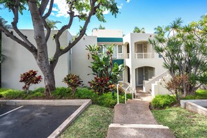 A building with a two-story structure, a staircase leading to the upper level, and a parking area in front. - Palms at Wailea #1605 Tropical Garden View Ground Floor, Wifi, Shared Hot Tub (Wailea)