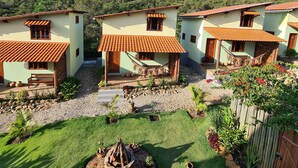 A row of houses with tiled roofs, a grassy yard, and a mountain in the background. - Green Chales (Palmeiras)