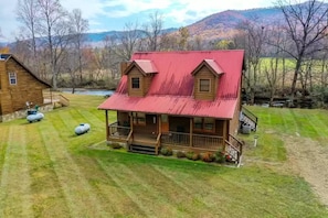 A wooden cabin with a red roof, a porch, and a small deck. - Mountain Creek #3584 by Aunt Bug's Cabin Rentals (Cosby)