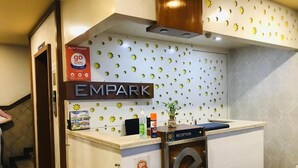 A reception desk with a 'go stays' sign, a reception area, and a wall with a sun pattern. - Hotel Empark (Bengaluru)