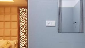 A bedroom with a bed, bedside table, and a decorative partition. A bathroom with a sink and mirror is visible. - Hotel Empark (Bengaluru)