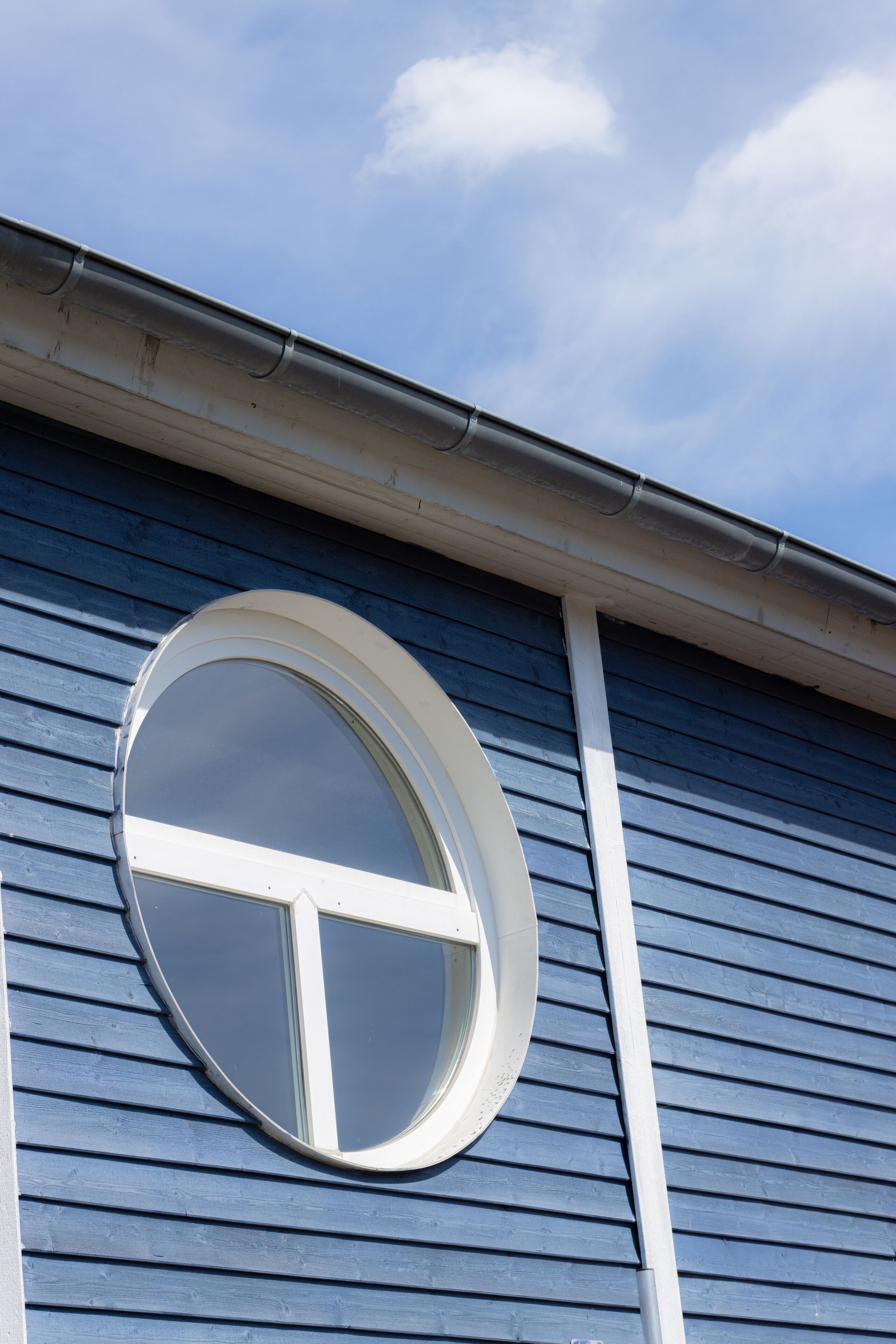 Een gebouw met een rond raam en horizontale gevelbekleding.