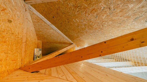 Un intérieur en bois avec un plafond en pente et des poutres apparentes.