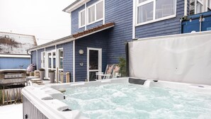 A hot tub in front of a blue house with a patio area.
