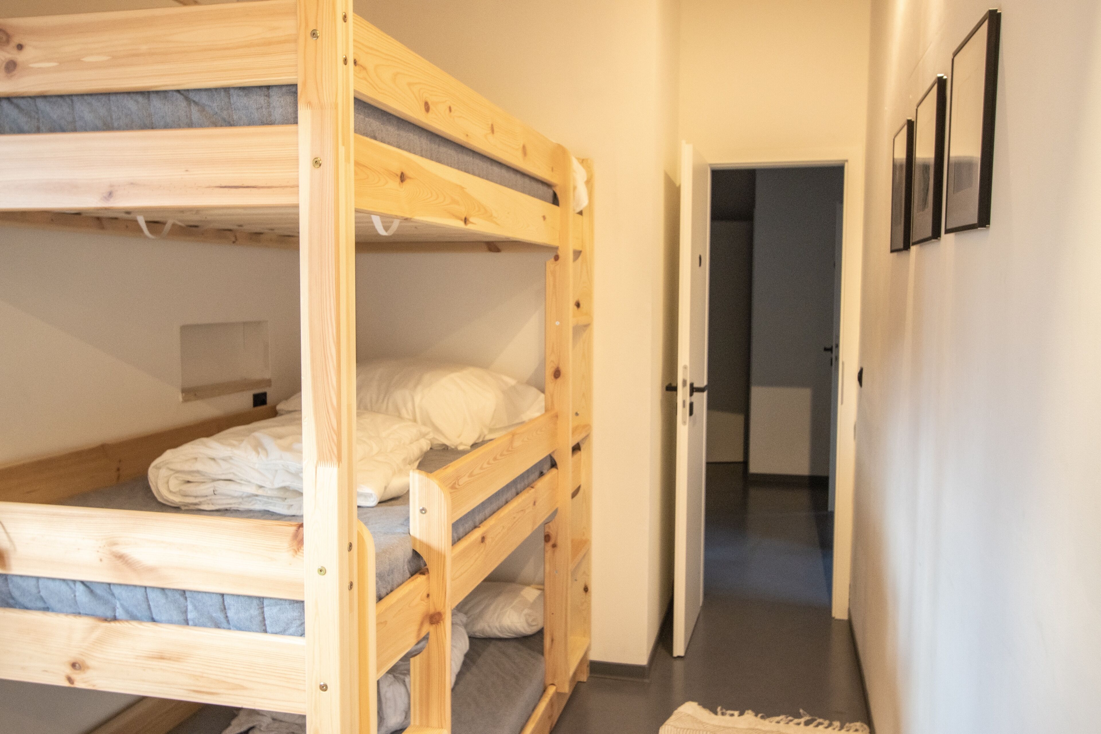Une chambre avec des lits superposés et une porte donnant sur une salle de bain.
