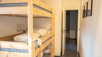 Une chambre avec des lits superposés et une porte donnant sur une salle de bain.