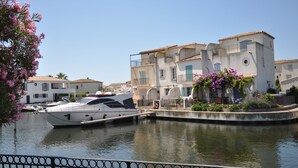 Un port de plaisance où est amarré un yacht blanc, entouré d’immeubles dotés de balcons, sous un ciel dégagé.