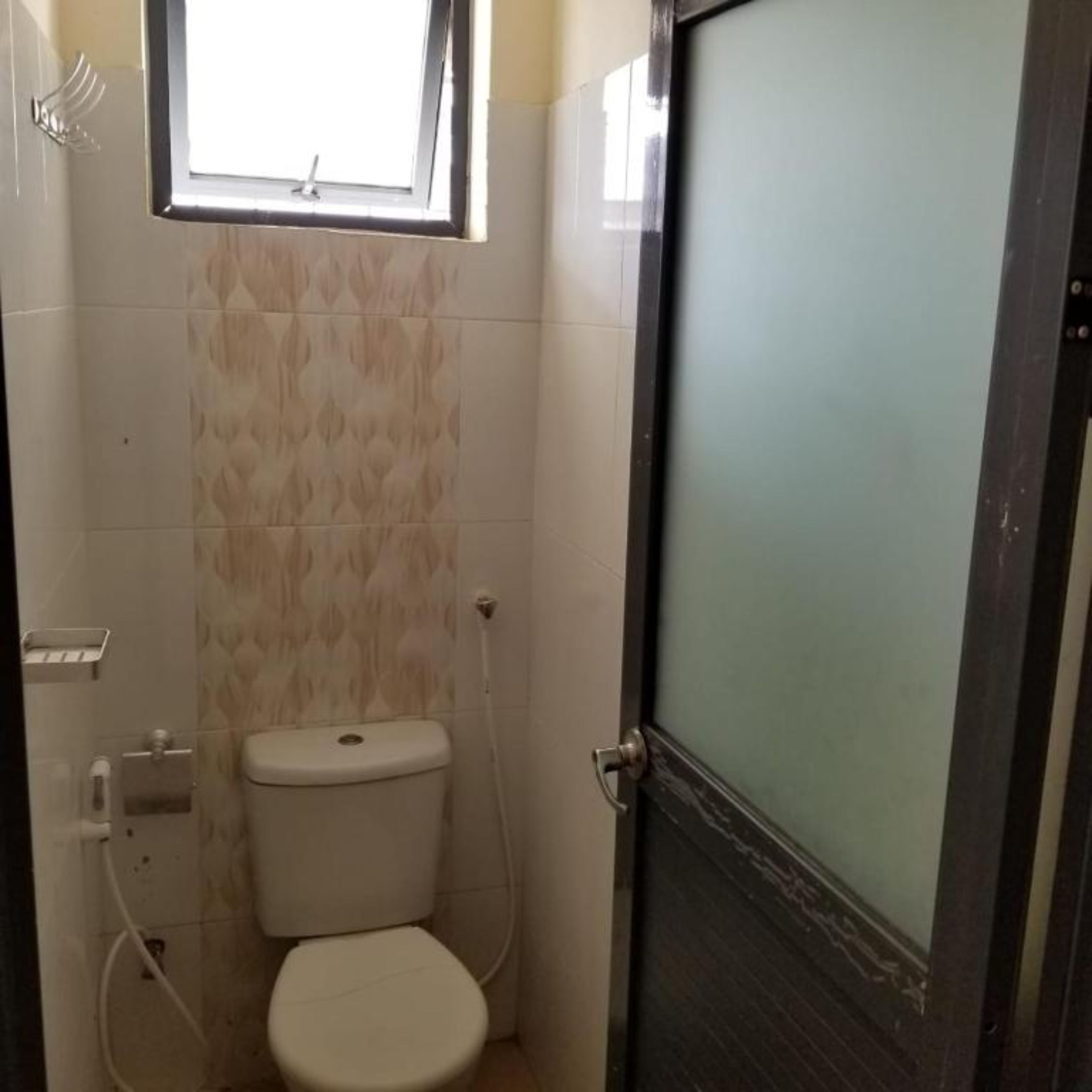 Casa de banho pequena e compacta, com sanita, janela e porta.