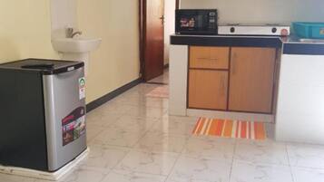 Una cocina compacta equipada con refrigerador, lavamanos y microondas.