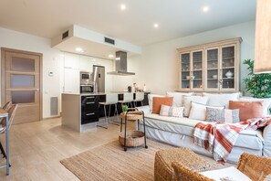A modern living room with a sofa, a dining area, and a kitchen.