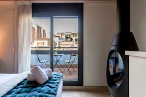 A hotel room with a bed, a balcony with a view of the city, and a black circular object on the wall.