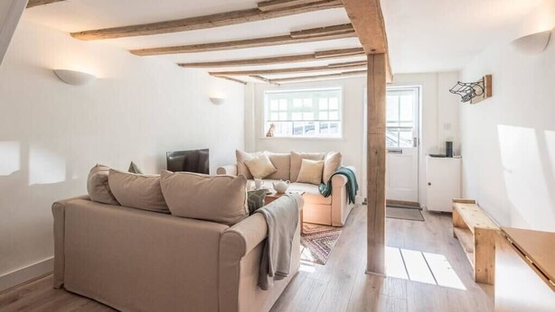 A cozy living room with a sofa, a smaller couch, and a wooden bench. There is a window providing natural light, and the room has exposed wooden beams on the ceiling. - Candy Cottage, Halesworth (Halesworth)